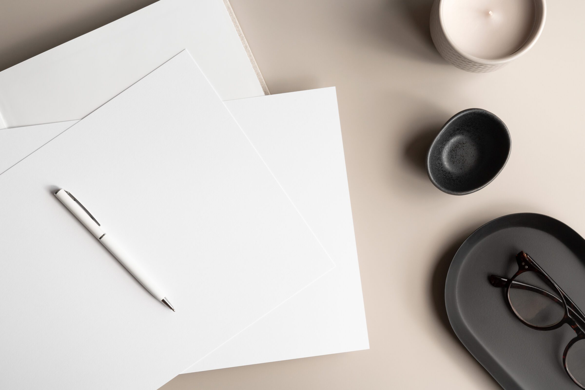 Open notebook with blank papers, a candle, and reading glasses, symbolizing the thoughtful preparation of packing for travel with kids by using a list to ensure nothing important is forgotten and to avoid overpacking, highlighting the strategic approach to how you pack for travel with kids.