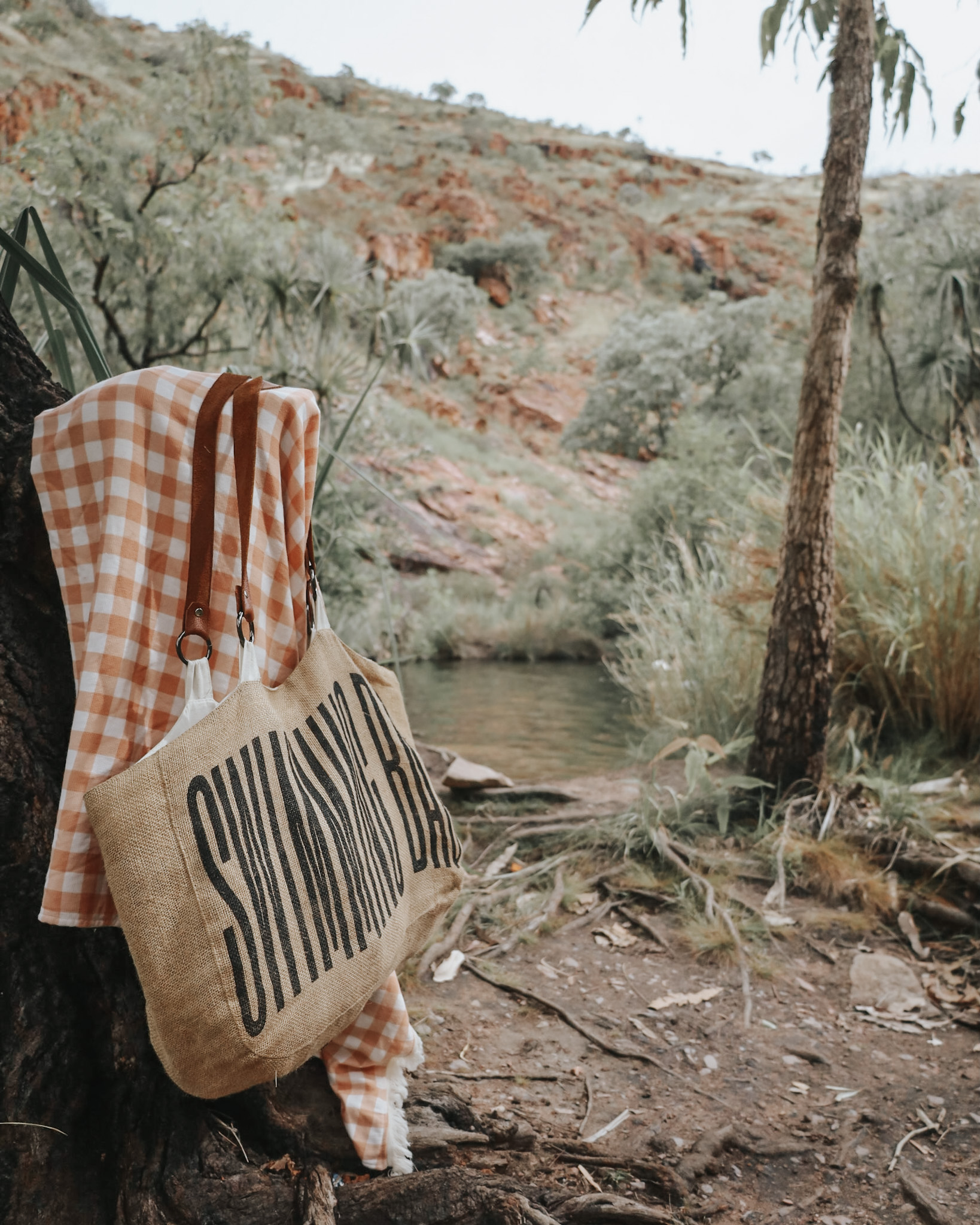 Secluded swimming spring in the Australian Kimberley, with a towel and bag hanging from a tree branch, showcasing that saving money is worth the effort to access breathtaking locations like this one.