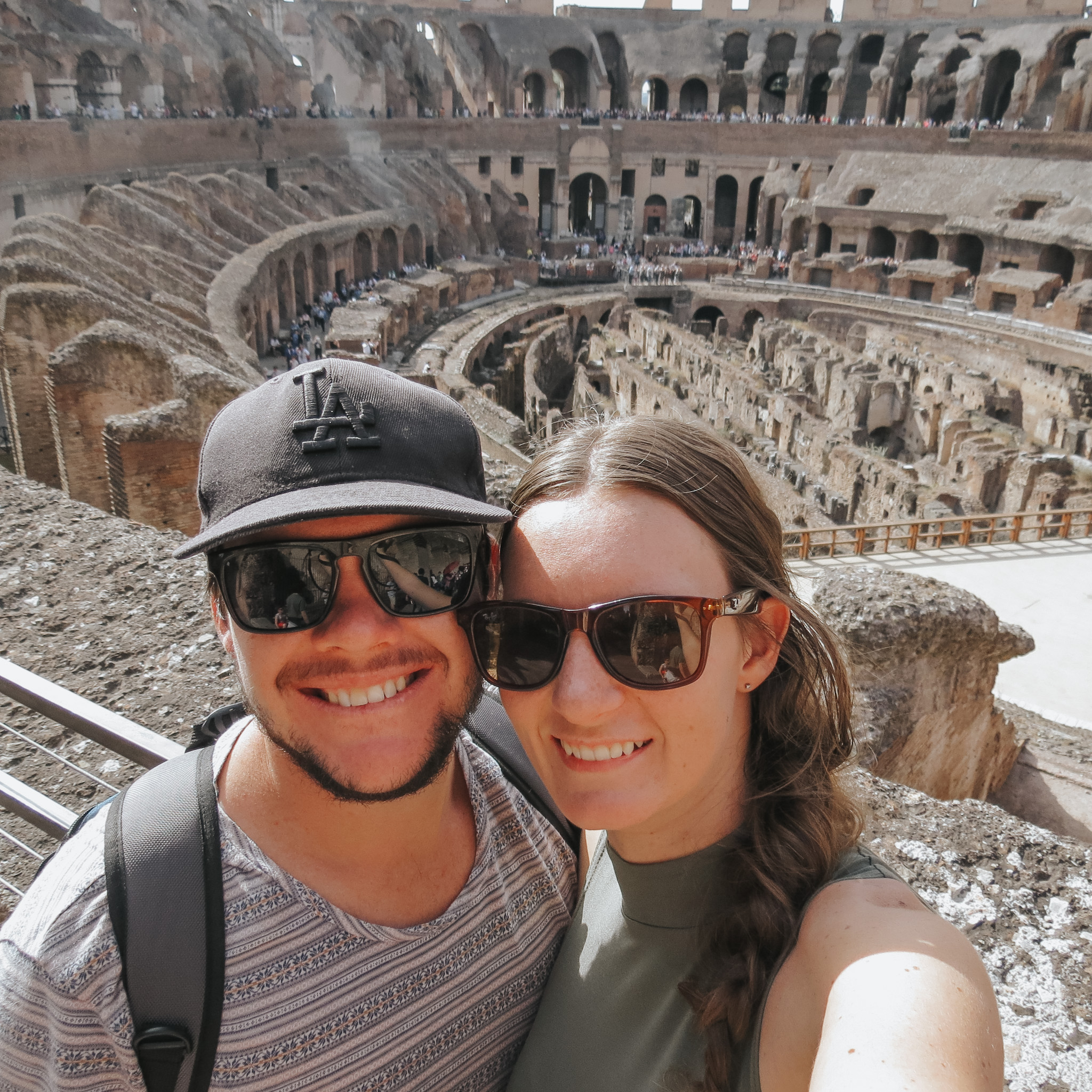 Man and woman couple at the Colosseum in Rome, symbolizing the high-low travel strategy by staying outside the city to save on accommodation, allowing for more spending on experiencing the iconic sights of Rome, as prioritized in their travel budget.