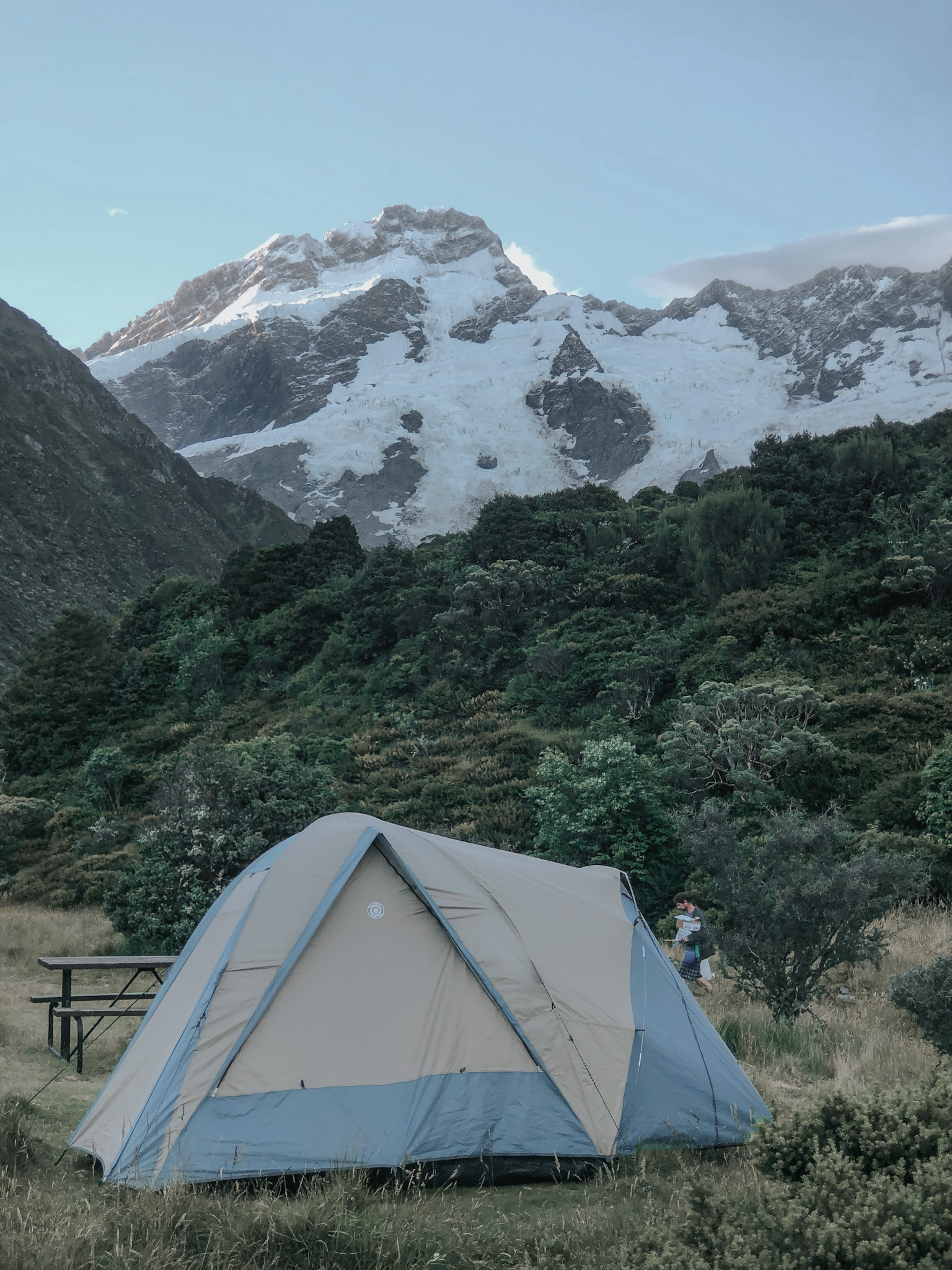 Small family tent pitched at a national park camping site in New Zealand with Mount Cook in the background, illustrating the 'low' aspect of high-low travel by combining affordable camping with high-end experiences.