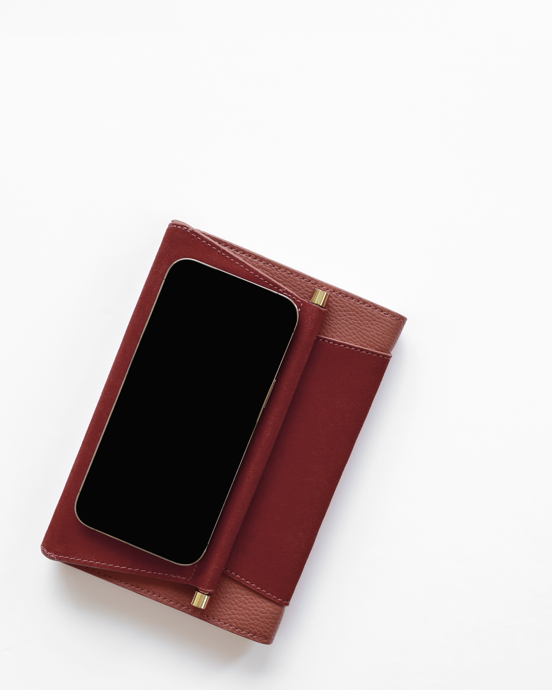 Brown women's clutch and a mobile phone on a bright white background, symbolizing the modern tools and essentials for efficiently managing money while travelling overseas.