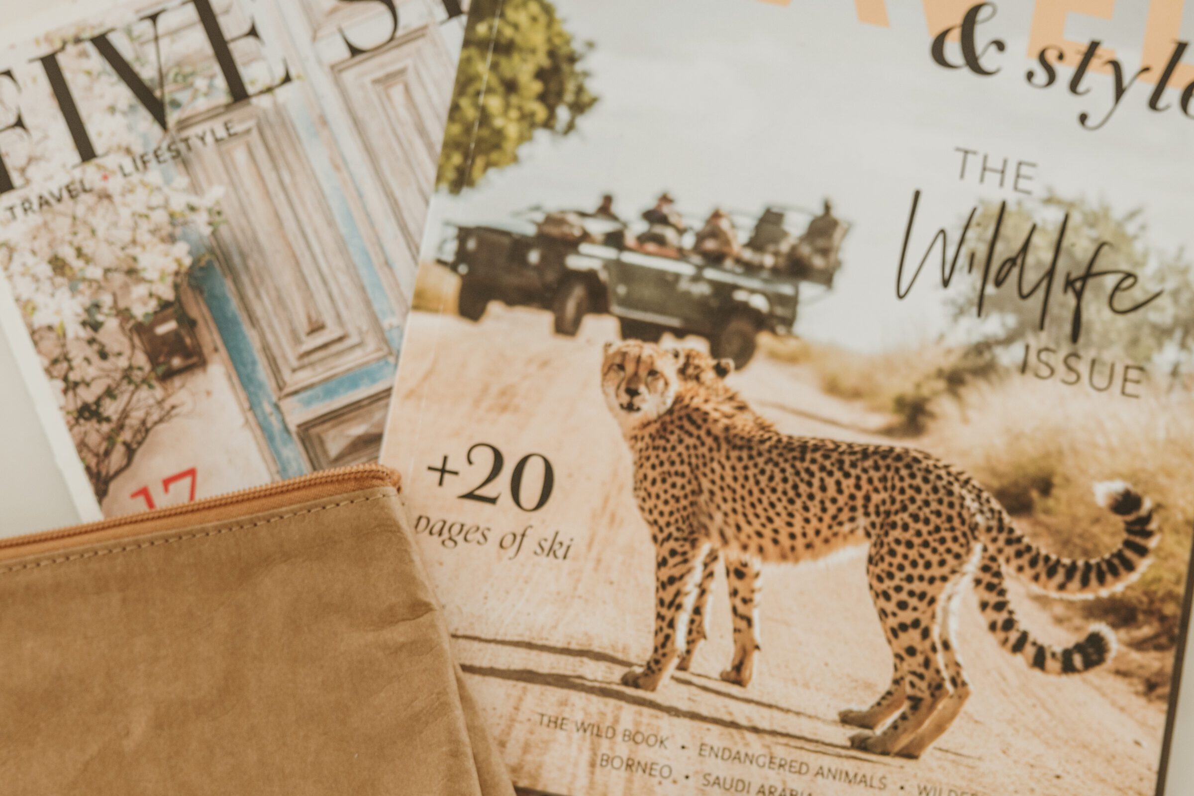 Two high-end travel magazines, 'Five-Star Travel' and 'Travel and Style Magazine', laid out for trip planning, symbolizing the 'high' aspect of the high-low travel method by offering inspiration for luxury travel experiences within a comprehensive travel strategy.