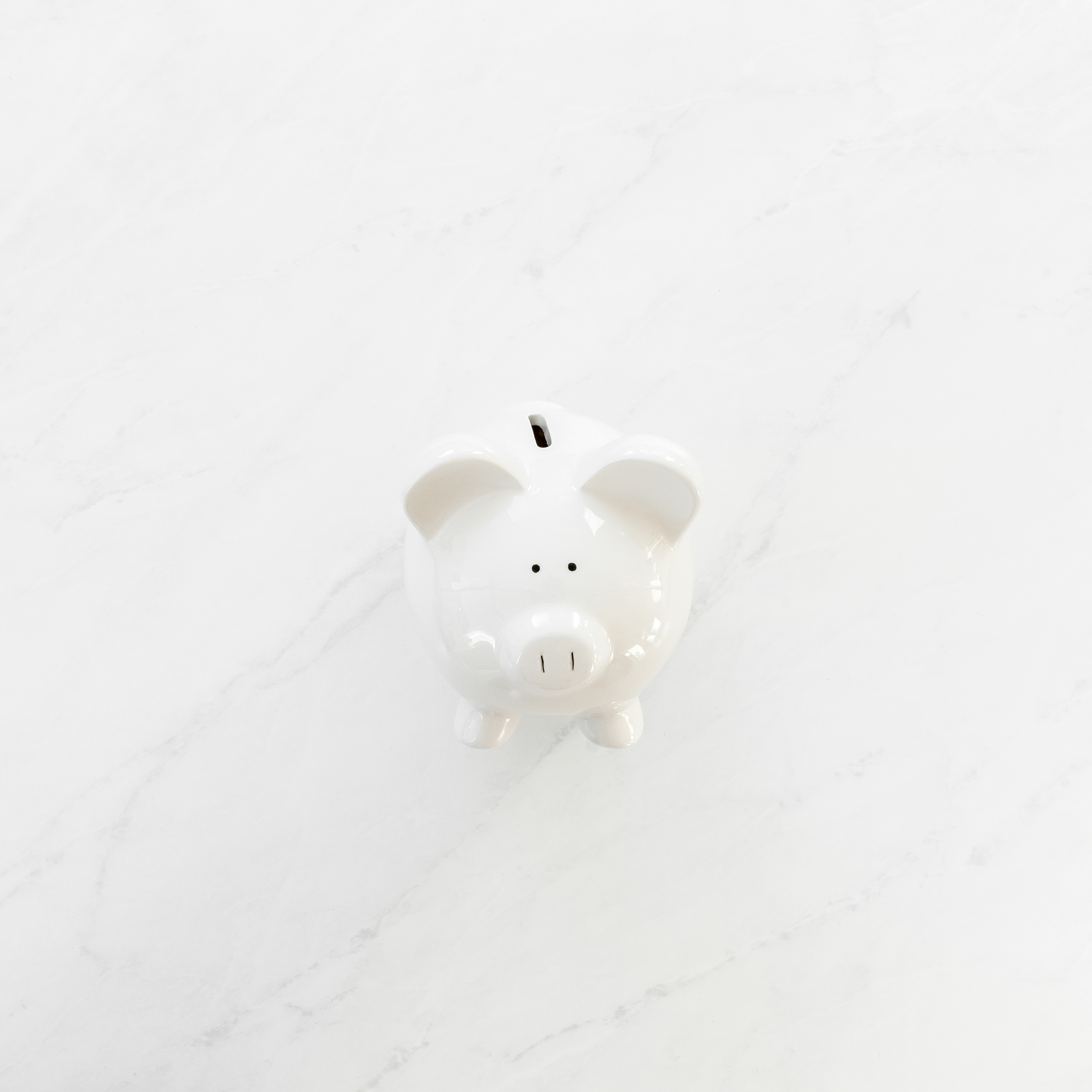 Ceramic white piggy bank on a white background, symbolizing the importance of starting a travel fund as part of planning for a family vacation, encouraging parents to save up for future travels.