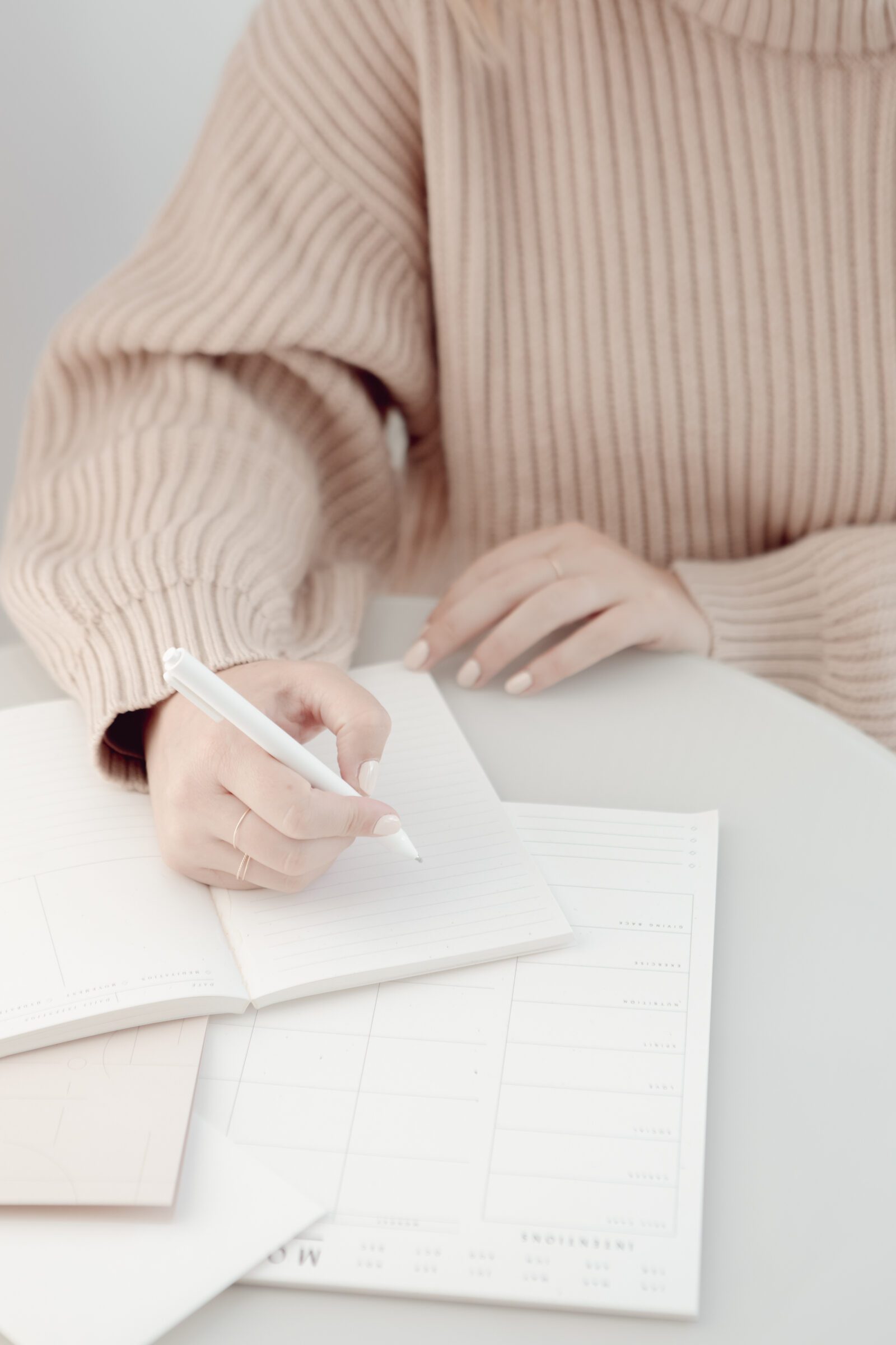 Woman sitting at a table with a notebook, about to outline her family's vacation goals and expectations, embodying the initial step in implementing high-low travel by determining priorities for a balanced blend of experiences.