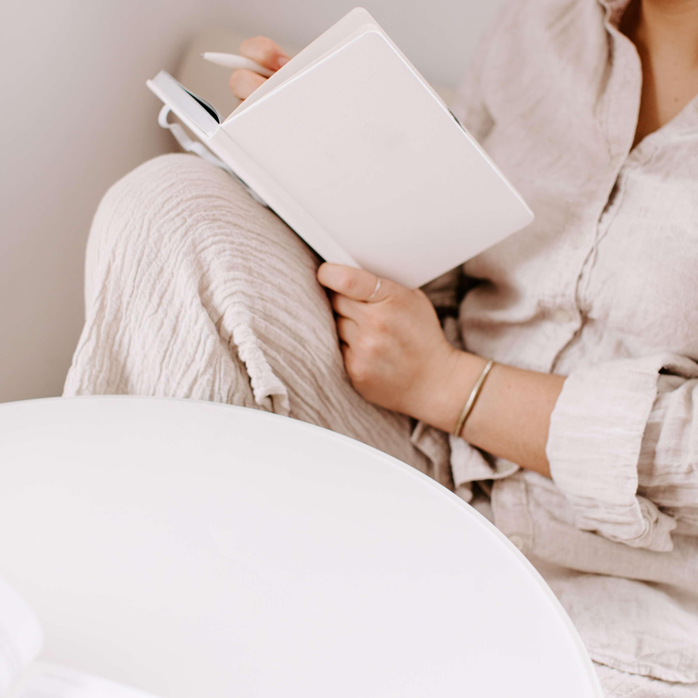 Woman sitting relaxedly with an open notebook and pen in hand, jotting down her high-low travel plan, illustrating the thoughtful preparation behind blending luxury and budget-friendly travel experiences.