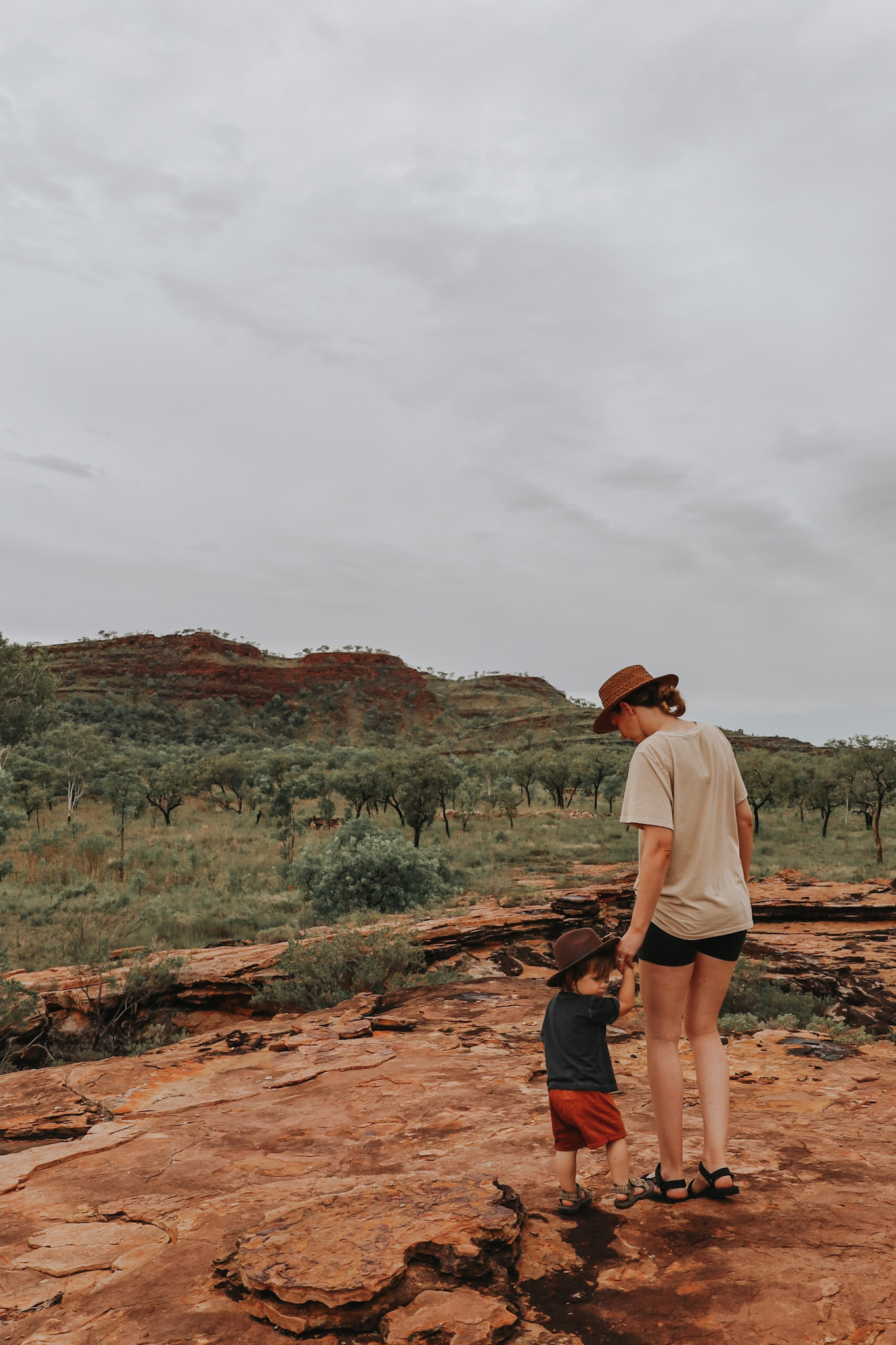 Mother holding her son's hand, guiding him across rocky terrain during a family hike, illustrating the importance of a family vacation through the shared experiences and support that strengthen family bonds and teach resilience.