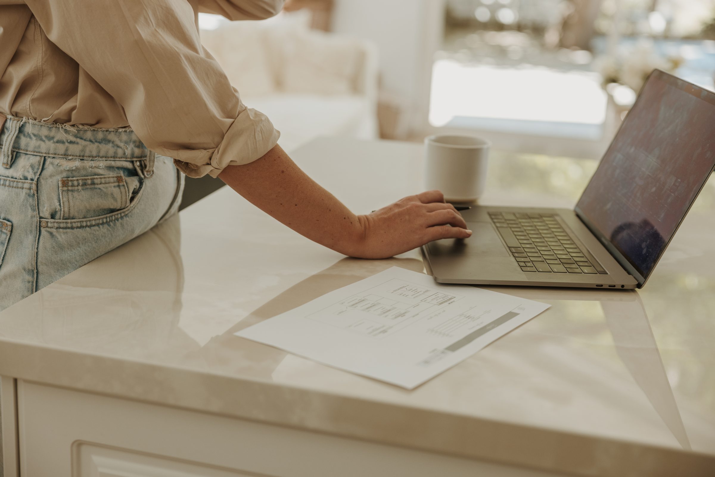 Woman finalizing her travel budget categories on a computer, with a spreadsheet beside her, illustrating the detailed planning involved in the high-low travel method, strategically allocating funds for a balanced and enriching travel experience.