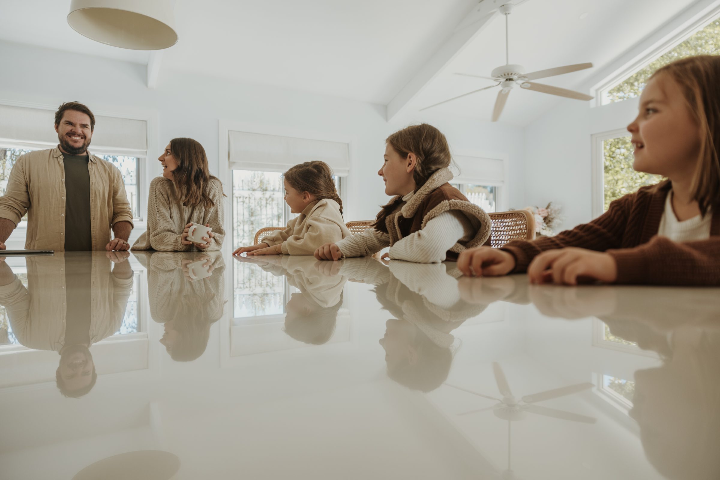 Family gathered around their kitchen island, engaging with each other as they thoughtfully plan a travel budget, highlighting the importance of aligning vacation choices with family needs and wants.