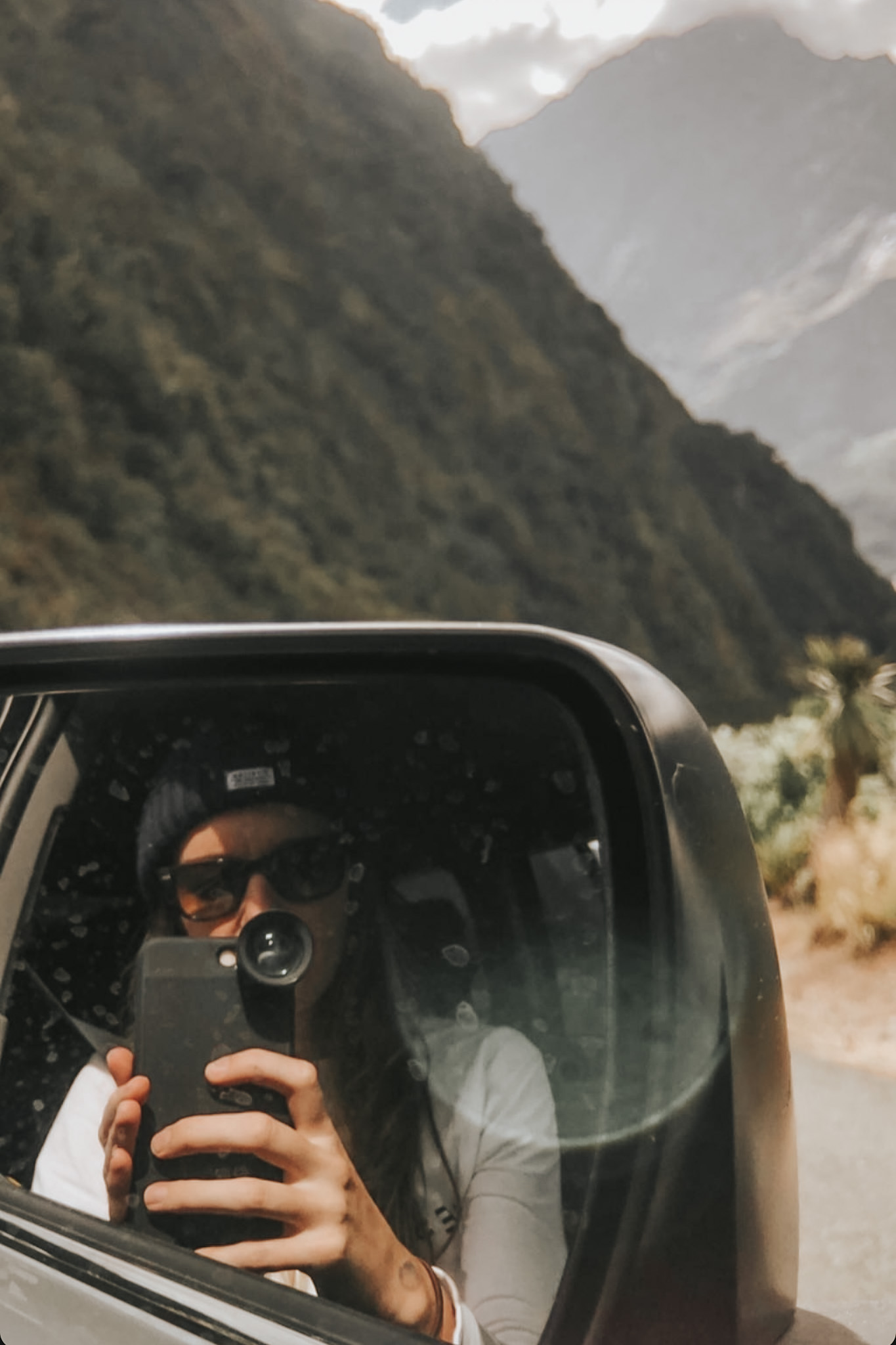 Woman in the passenger seat of a car, with mountains in the background during a family road trip, highlighting transportation as a significant expense in a family travel budget. This image emphasizes the importance of planning for travel costs to ensure all aspects of the journey are covered.