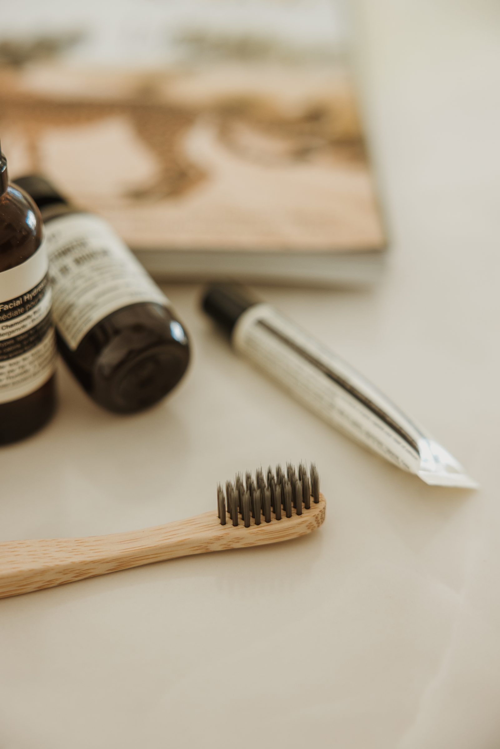 Two small travel-sized toiletry bottles, a mini toothpaste tube, and a toothbrush with a travel magazine in the background, highlighting the importance of a solid toiletries system in packing for travel with kids, simplifying preparations and reducing stress.