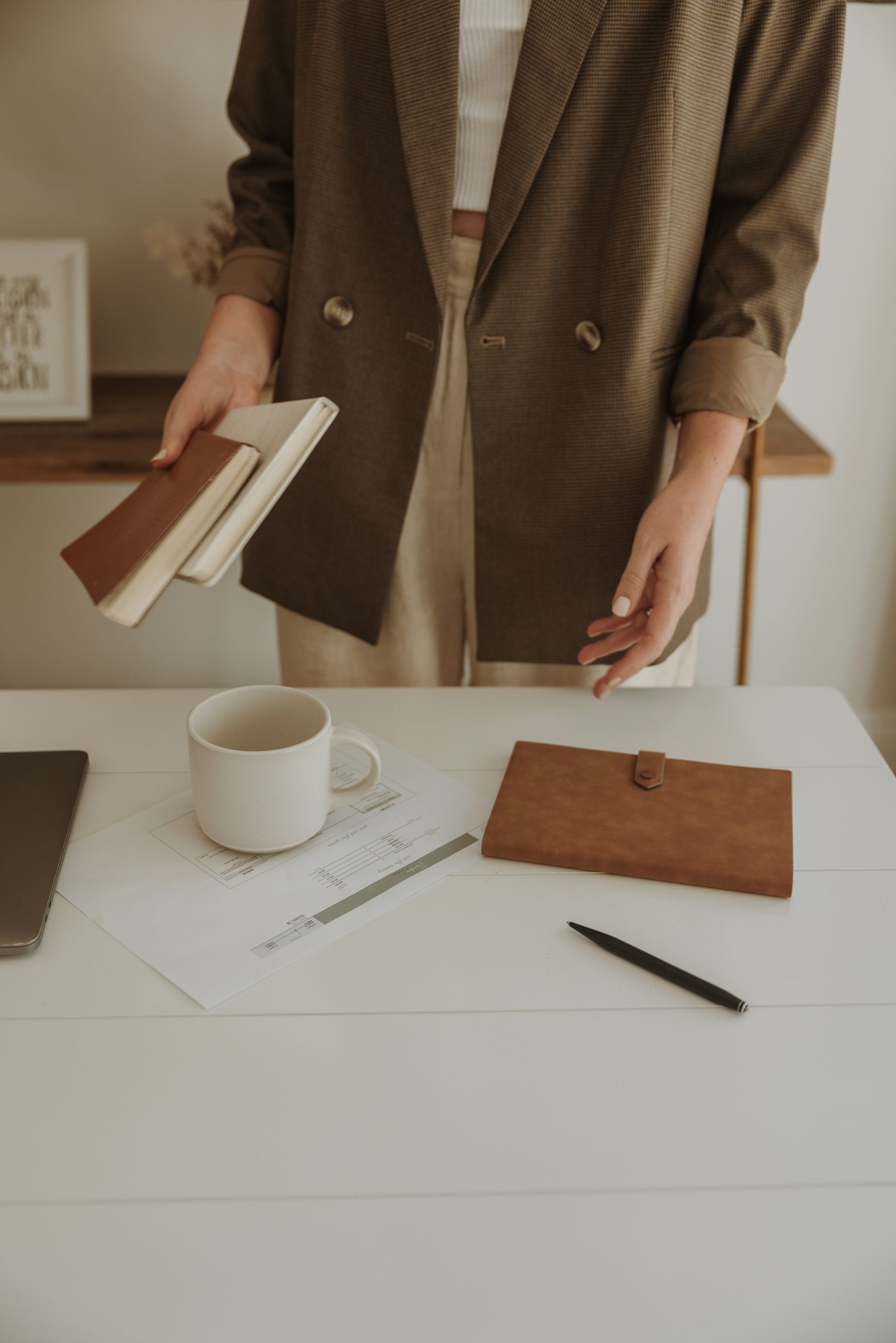 Woman standing at her desk with a budgeting spreadsheet and notebooks, finalizing her family travel budget. This image captures the decision-making process involved in 'how to create a family travel budget,' emphasizing the adjustments necessary to align travel plans with what the family can afford.