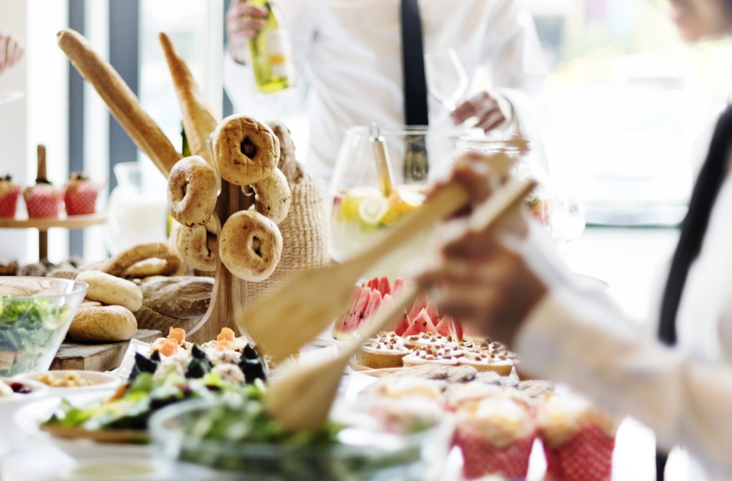 Buffet breakfast at a hotel, with staff organizing food in the background, showcasing how utilizing a hotel with free breakfast can help afford your next family vacation. This amenity removes one meal from your daily expenses and provides extra snacks for later, making it a cost-effective choice for families and stretching the travel budget further.