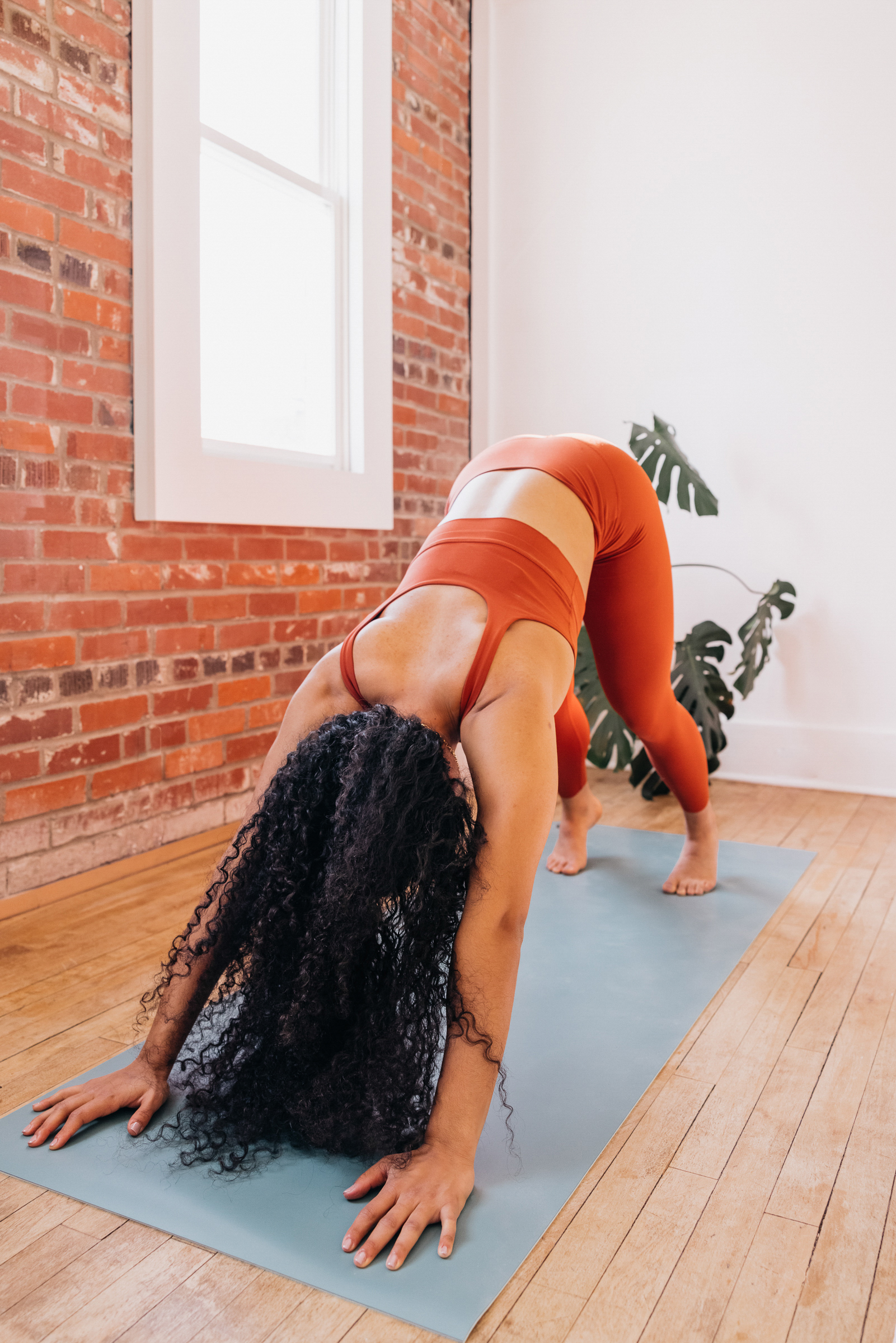 Woman practicing pilates at home, opting for free online workout videos over paid fitness memberships to save money for travel. This image encourages exploring cost-effective fitness alternatives to allocate funds towards travel goals, promoting financial discipline while maintaining wellness routines.