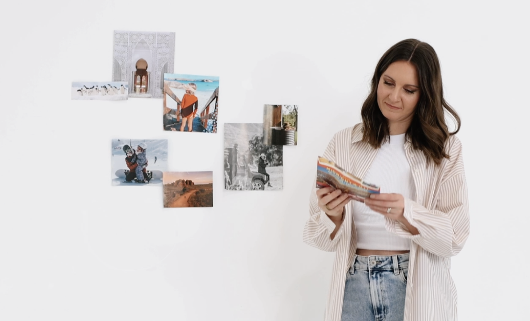 Woman building a travel vision board by sticking up photos of dream destinations, inspiring travel quotes, and activities, highlighting the power of visualization in keeping travel goals at the forefront of saving efforts.