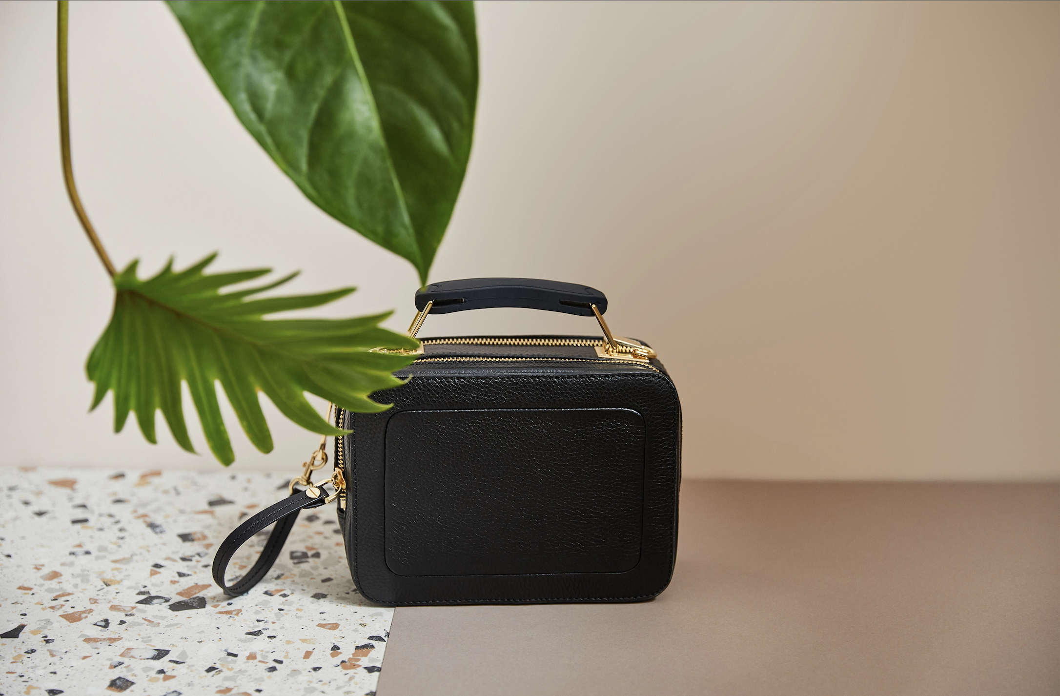 Black handbag on a desk with a plant in the background, symbolising the end of preparations in the financial travel checklist and ready-to-go organisation for an overseas trip.