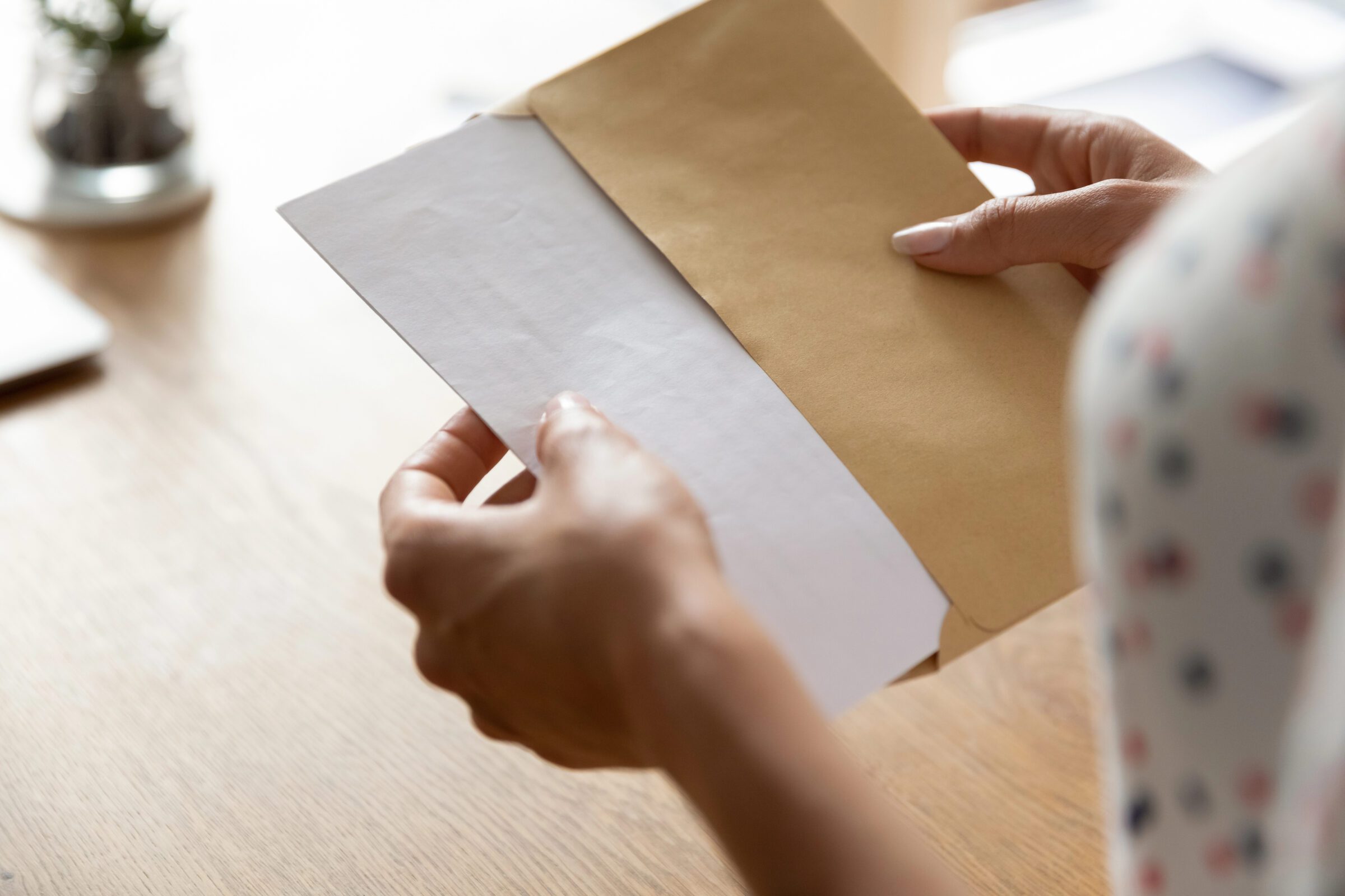 Hands of a woman opening a large envelope containing copies of passports, insurance, and card details, part of a financial travel checklist to share important documents with a trusted contact while travelling overseas.