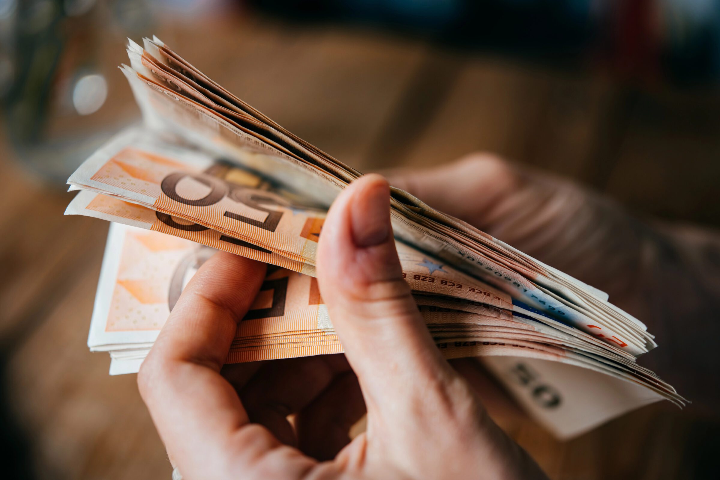 Hands holding European euro bills, showing the importance of having some local currency on arrival while following a travel money system for emergencies and small payments.