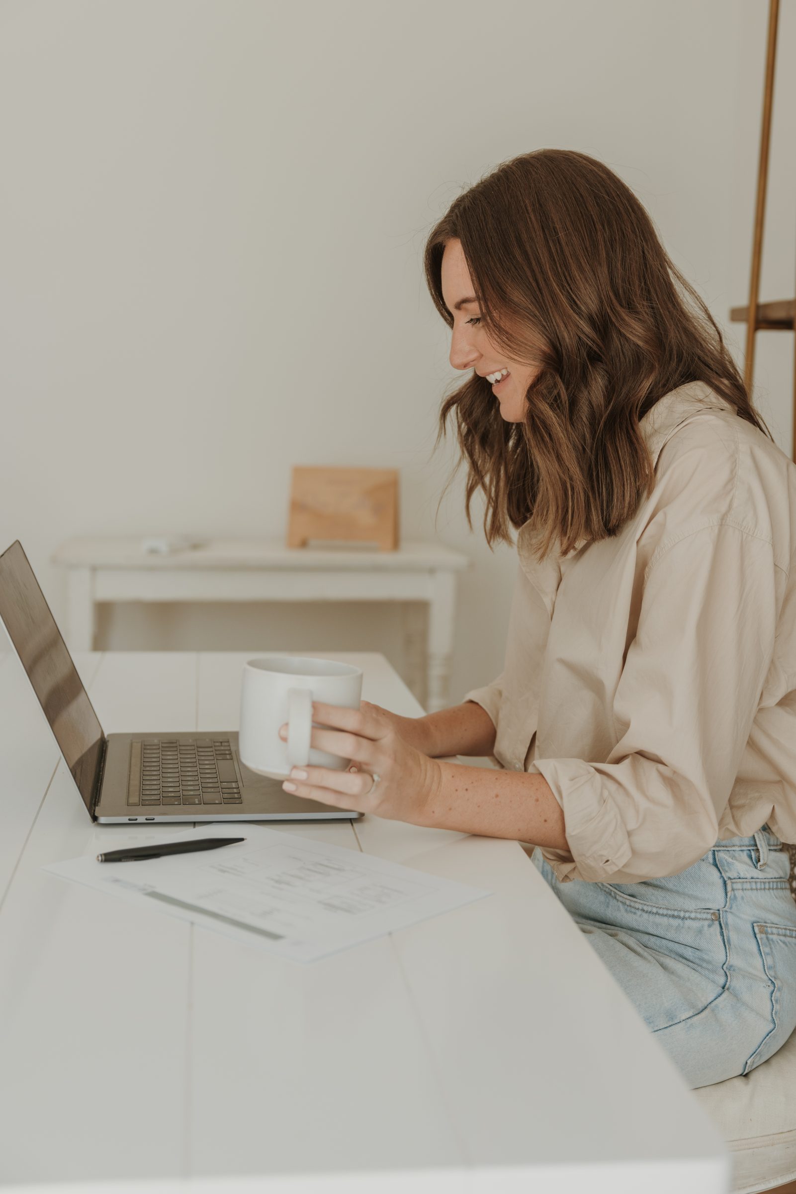 Woman sitting at her desk, working on her laptop and organising her family travel budget, finalising expenses and emergency funds as part of a financial travel checklist for smart overseas planning.