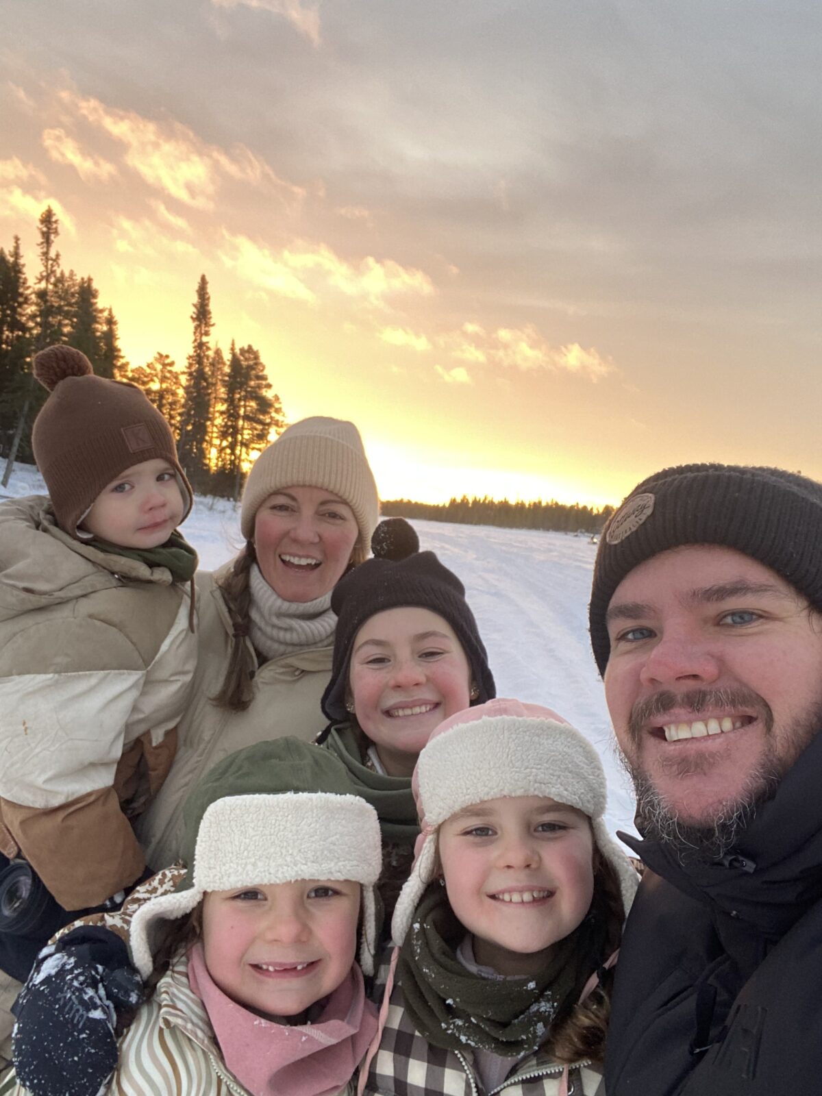 Our family standing on a frozen lake in Finland at sunset, illustrating how researching a destination in detail helps plan costs, prioritise experiences, and balance spending on meals, activities, and transport.