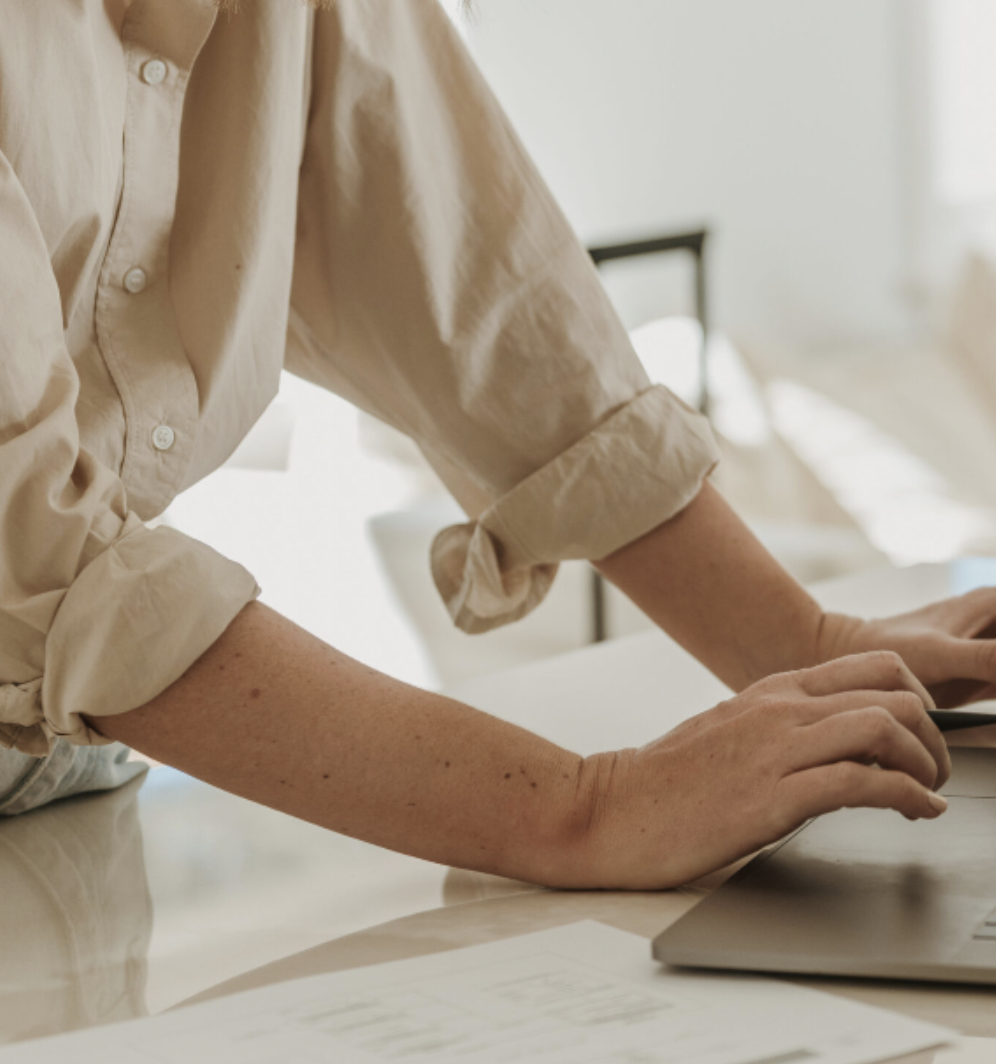 Woman typing at her laptop, tracking monthly expenses to grow her travel fund, illustrating the step of writing down every expense for a clear picture of household spending.