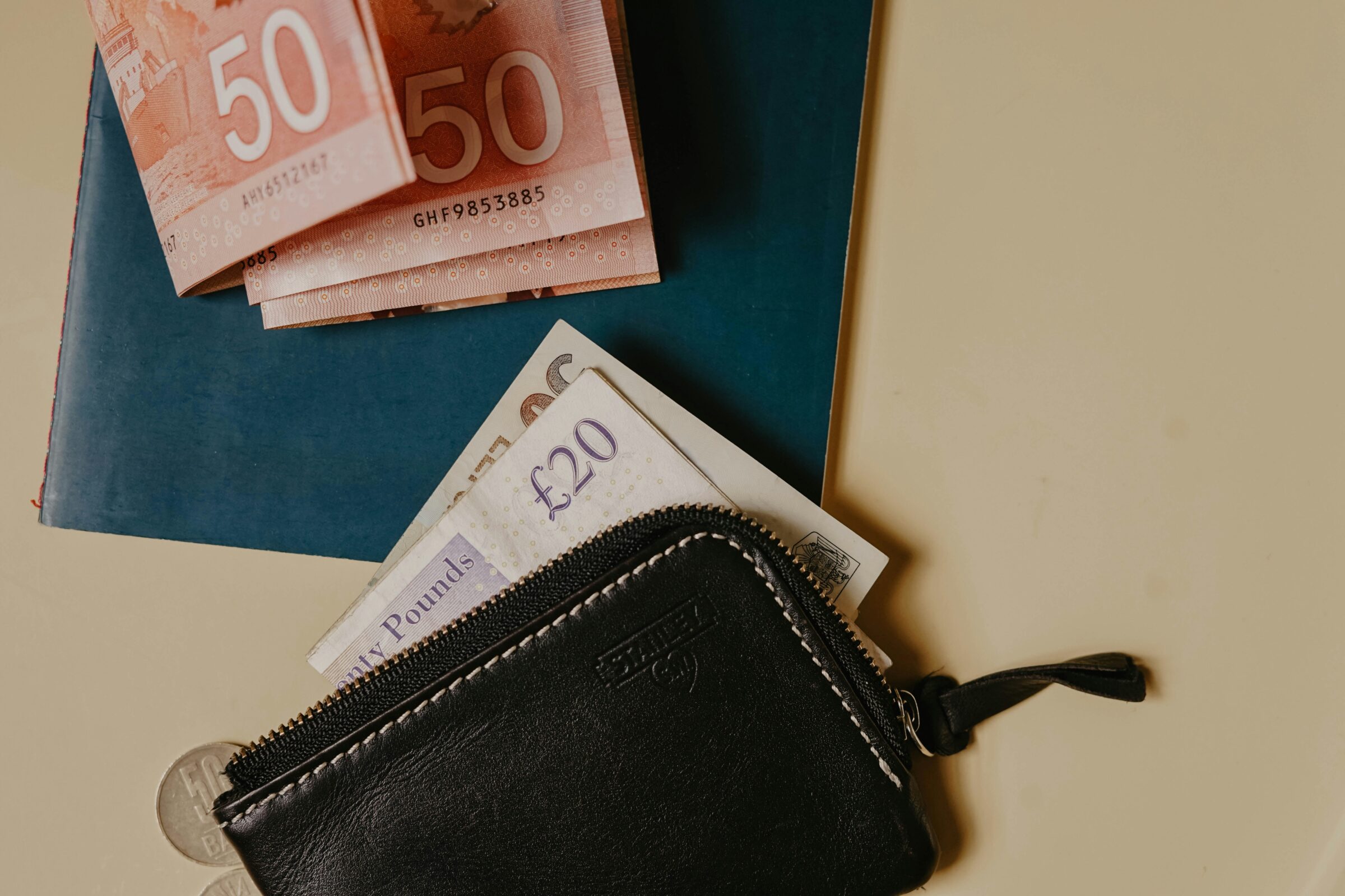 Wallet containing mixed currencies and a passport, highlighting the travel tip to keep some emergency cash separate from daily spending money.